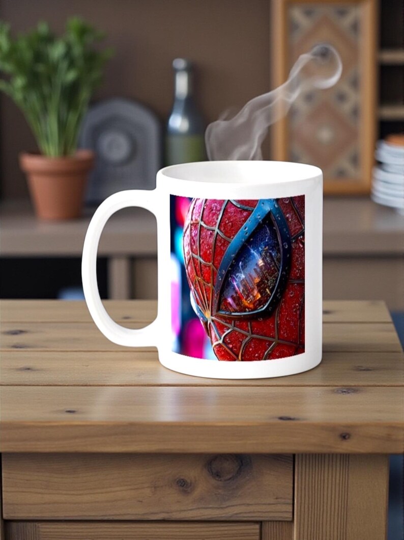 May include: White ceramic mug featuring a close-up of Spider-Man's mask, with red webbing and a blue eye. Steam rises from the mug, suggesting a hot beverage. The mug sits on a wooden table.