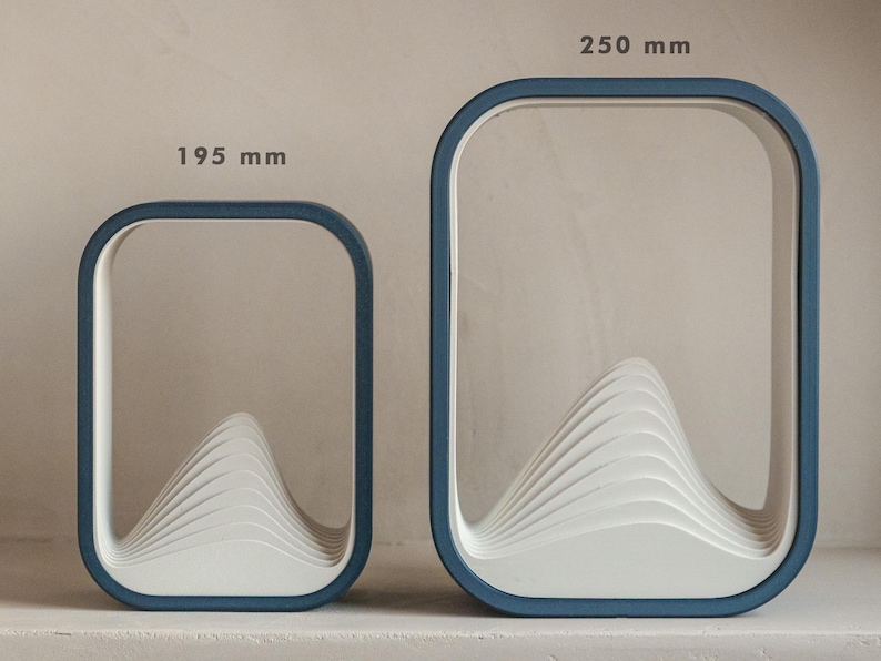Puede incluir: Dos marcos decorativos rectangulares modernos con esquinas redondeadas. Los marcos tienen un borde azul y un dise&ntilde;o blanco en capas en forma de monta&ntilde;a en el interior. El marco m&aacute;s grande mide 25 cm de alto, y el m&aacute;s peque&ntilde;o, 19,5 cm.