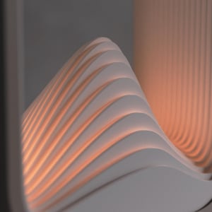 Puede incluir: Escultura abstracta moderna con un dise&ntilde;o en forma de ola. Compuesta por paneles blancos curvos y superpuestos, iluminados por un c&aacute;lido resplandor naranja desde el interior. La pieza est&aacute; enmarcada por un borde rectangular oscuro.