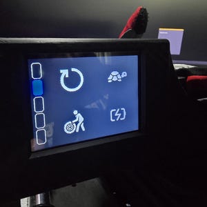 Pu&ograve; includere: Uno schermo digitale nero che mostra un'interfaccia blu con icone bianche. Le icone includono una freccia circolare, una tartaruga, una persona che lavora con uno pneumatico e un simbolo di fulmine. &Egrave; visibile una colonna verticale di cinque caselle.
