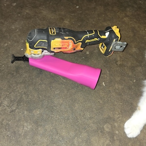 May include: A yellow and black cordless oscillating multi-tool with a 20V battery pack attached, featuring a black metal cutting blade inserted into a bright pink, tapered, cylindrical plastic sleeve or guard extending from the tool head.
