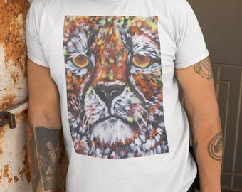 Op de afbeelding: Wit T-shirt met een kleurrijke afbeelding van een cheeta's gezicht. De illustratie toont de ogen, neus en vacht van het dier in tinten oranje, geel, rood en wit. Het shirt heeft een ronde hals.