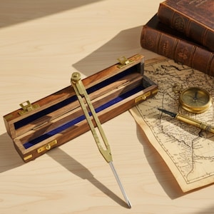 May include: A vintage brass proportional divider with a wooden case, open to reveal a blue velvet interior. A map, compass, and antique books are also on the wooden surface, suggesting a theme of exploration and navigation.