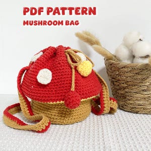 May include: A handmade crochet mushroom bag with a red cap and white polka dots. The bag has a tan base and strap, with the text "PDF PATTERN MUSHROOM BAG" in red. The bag is a whimsical accessory.