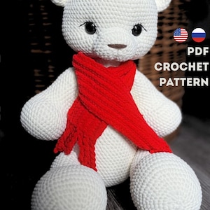 Puede incluir: Un oso blanco de ganchillo con una bufanda roja. El oso tiene ojos negros y una nariz marrón. La imagen incluye el texto "PDF CROCHET PATTERN" y las banderas de EE. UU. y Rusia. Es un juguete blando.