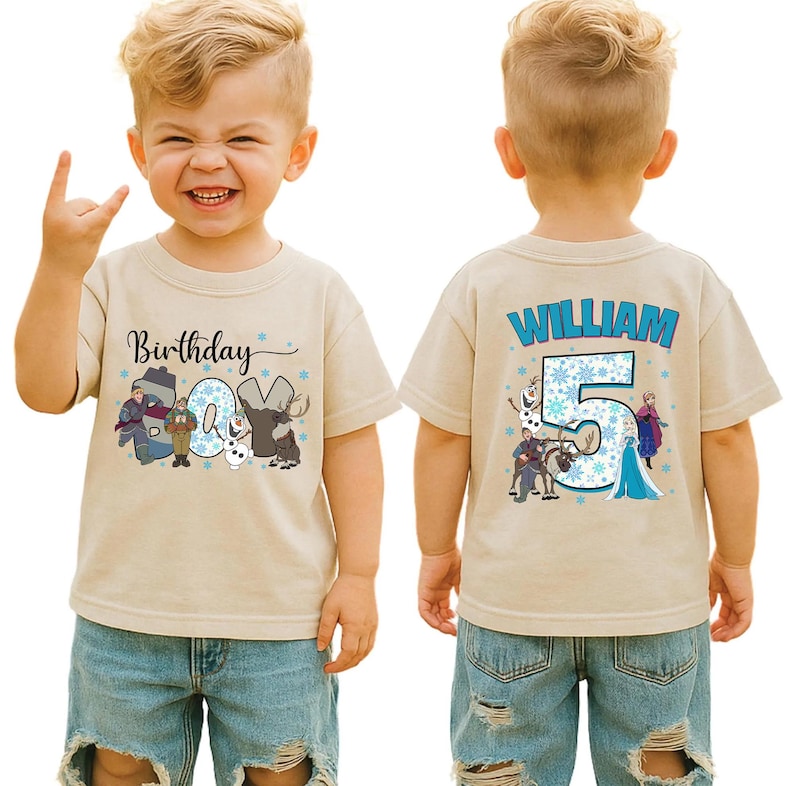 May include: A tan short-sleeved t-shirt featuring a colorful graphic design. The front of the shirt says "Birthday 5" with cartoon characters. The back of the shirt says "WILLIAM" and "5" with cartoon characters.