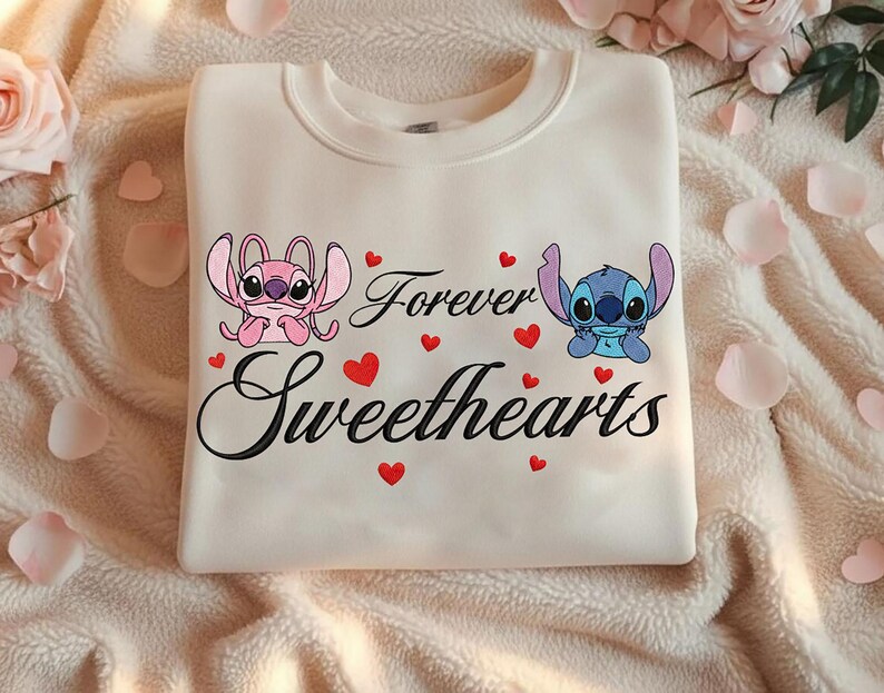 Może przedstawiać: Kremowa bluza z postaciami Angel i Stitch, napisami "Forever Sweethearts" i czerwonymi serduszkami. Projekt jest wyśrodkowany na przodzie bluzy.