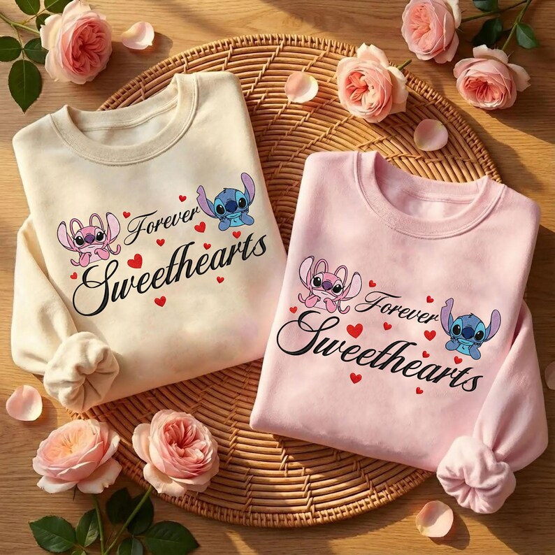 Może przedstawiać: Dwie bluzy z okrągłym dekoltem, jedna kremowa i jedna r&oacute;żowa, z napisem "Forever Sweethearts" i postaciami z kresk&oacute;wek. Projekt zawiera czerwone serca i postacie Stitcha i Anioła. Bluzy są prezentowane na tkanej macie z r&oacute;żowymi r&oacute;żami.