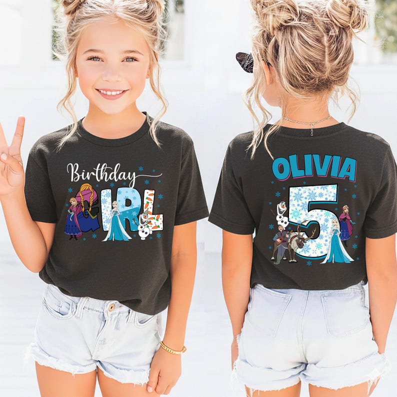 May include: A dark gray t-shirt with the words "Birthday Girl" and the name "Olivia" printed on it. The front of the shirt has a graphic of characters from a popular animated movie. The back of the shirt has the number "5" with characters from the same movie.