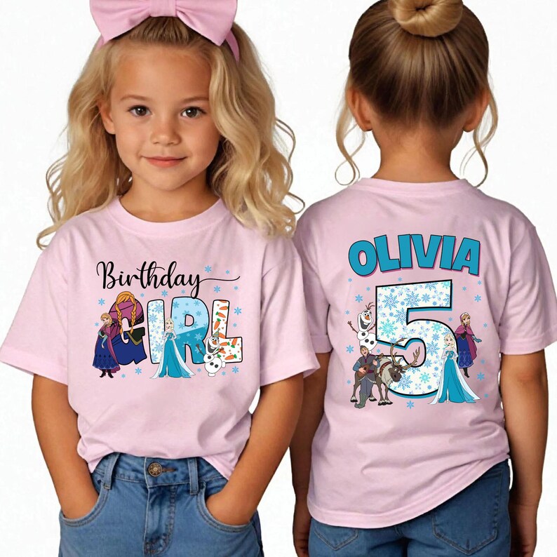 May include: Pink short-sleeved t-shirts with a graphic design featuring characters and text from the movie Frozen. One shirt says "Birthday Girl" and the other says "Olivia 5". The shirts are worn by young children.