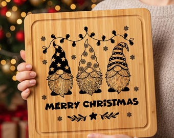 May include: A square bamboo cutting board featuring a black laser-engraved design of three gnomes wearing patterned hats under a string of lights. The text MERRY CHRISTMAS is printed below the gnomes, surrounded by small snowflake and leaf accents.