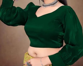 May include: A dark green long-sleeved blouse with a V-neckline and voluminous puff sleeves featuring fitted cuffs. The garment is paired with a yellow patterned skirt, a silver-toned choker necklace, and a silver-toned bracelet on the wrist.
