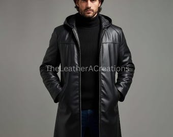 May include: A black leather hooded coat with a zipper closure. The coat is long, reaching the knees, and has two front pockets. The model is wearing a black turtleneck sweater and blue jeans. The text "The LeatherACreations" is visible on the coat.