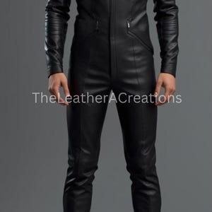 May include: A black leather jumpsuit with a high collar and a front zipper. The jumpsuit has long sleeves and fitted pants. The text "TheLeatherACreations" is visible on the garment. The overall style is sleek and modern.