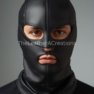 May include: A black leather hood with eye and mouth openings. The hood covers the head and neck, with a vertical seam down the centre. The text "TheLeatherACreations" is visible at the bottom left.