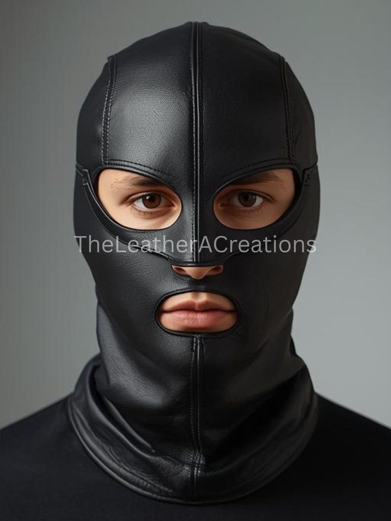 May include: A black leather hood with eye and mouth openings. The hood covers the head and neck, with a vertical seam down the centre. The text "TheLeatherACreations" is visible at the bottom left.