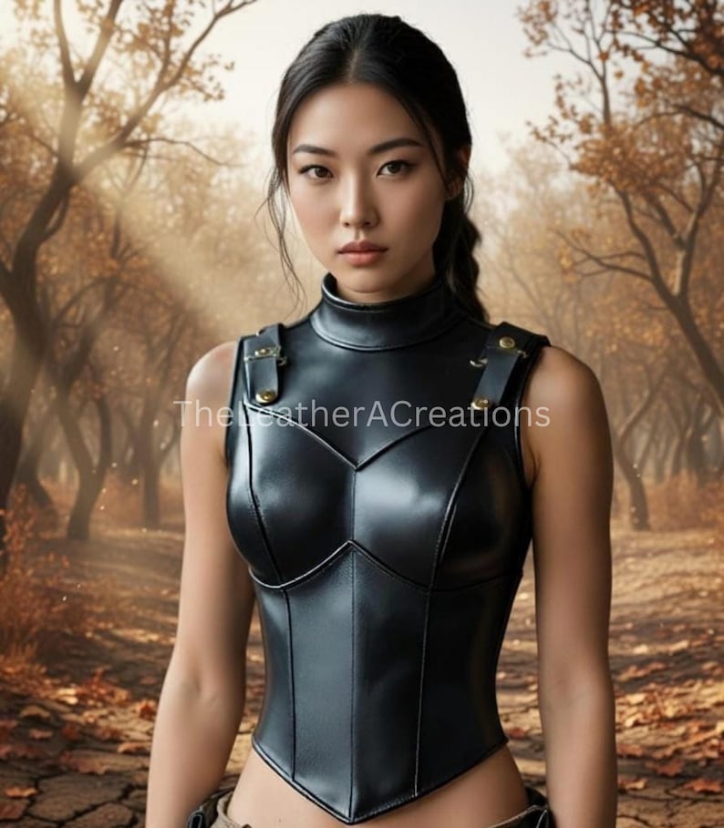 May include: A black leather corset with a high collar and shoulder straps. The corset has a structured design with a V-shaped neckline and is adorned with gold-colored hardware. The image is set against a blurred outdoor background with trees.