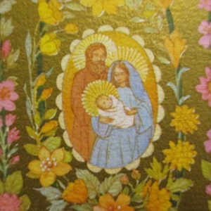 Puede incluir: Icono religioso que representa la Sagrada Familia, rodeado por un borde floral. La imagen central muestra a Mar&iacute;a sosteniendo al ni&ntilde;o Jes&uacute;s, con Jos&eacute; a su lado. El fondo es dorado y las flores son rosas, amarillas y naranjas.