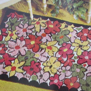 May include: A colorful floral rug with a black scalloped border. The rug features a pattern of red, pink, yellow, and green flowers. The rug is placed on a yellow surface.
