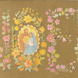 Puede incluir: Una tarjeta navide&ntilde;a dorada con la palabra "NOEL" escrita con flores coloridas. La letra "O" enmarca una imagen de la Sagrada Familia. La tarjeta tiene una superficie texturizada.