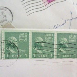 Op de afbeelding: Close-up van groene vintage postzegels met een profiel van George Washington, met de tekst "United States Postage" en "1 Cent". Poststempels uit Denver en Tacoma, gedateerd 1948, zijn ook zichtbaar op de envelop.