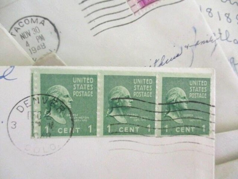 Op de afbeelding: Close-up van groene vintage postzegels met een profiel van George Washington, met de tekst "United States Postage" en "1 Cent". Poststempels uit Denver en Tacoma, gedateerd 1948, zijn ook zichtbaar op de envelop.