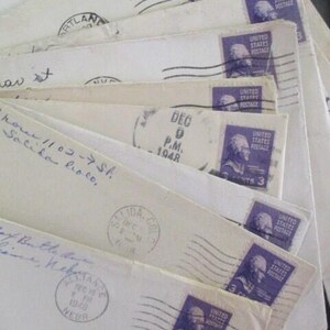 Op de afbeelding: Een verzameling vintage enveloppen, uitgespreid om de details te laten zien. Elke envelop heeft een paarse 3-cent postzegel met een portret. De enveloppen zijn afgestempeld met data uit 1948 en bevatten handgeschreven adressen en postmarkeringen.