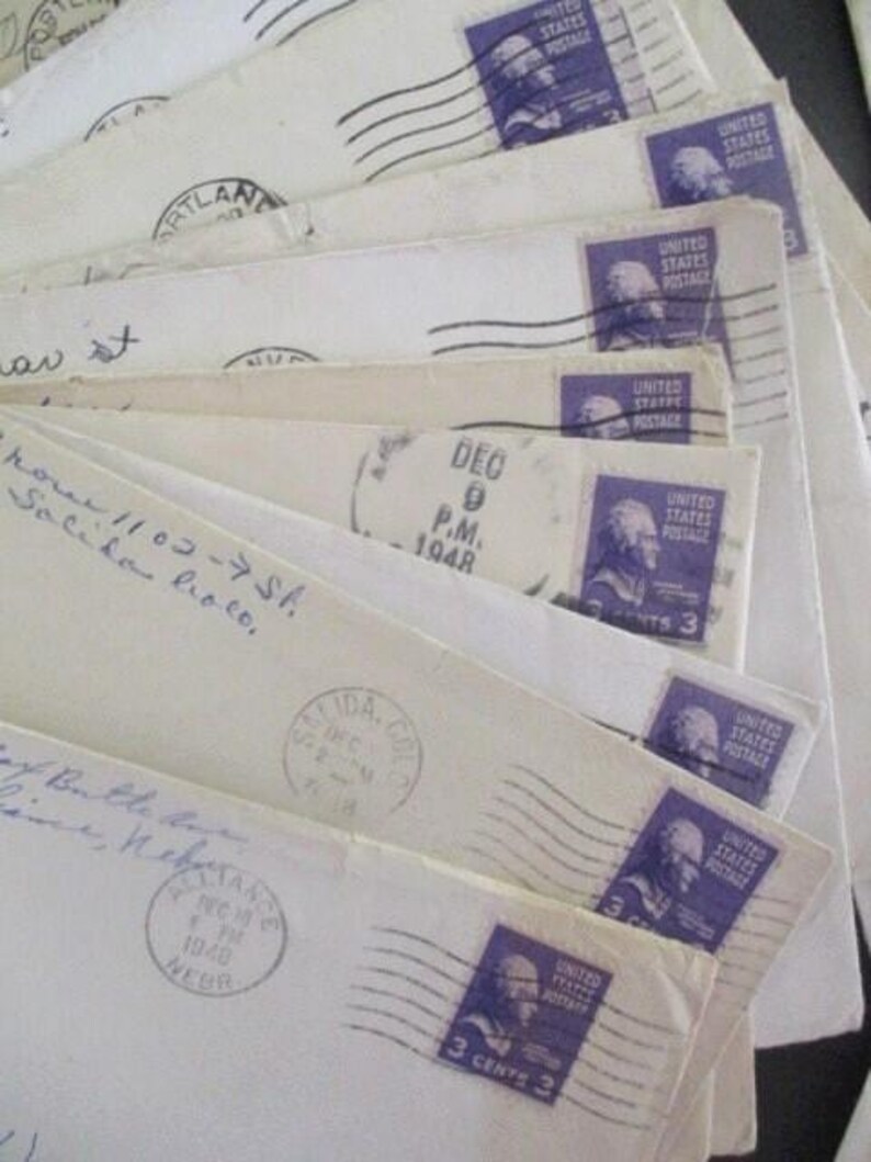 Op de afbeelding: Een verzameling vintage enveloppen, uitgespreid om de details te laten zien. Elke envelop heeft een paarse 3-cent postzegel met een portret. De enveloppen zijn afgestempeld met data uit 1948 en bevatten handgeschreven adressen en postmarkeringen.