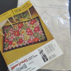 May include: A vintage rug-making kit with a floral design. The kit includes a pattern, yarn, and a punch needle. The pattern shows a finished rug with red, pink, yellow, and green flowers. The rug size is 34 x 48 inches.