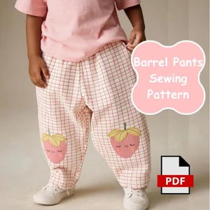 May include: Barrel trousers with a white and red grid pattern, featuring embroidered pink strawberry graphics on each leg. The trousers are paired with a plain light pink t-shirt. A pink graphic overlay displays the text Barrel Pants Sewing Pattern.