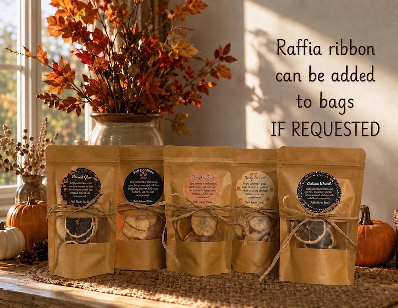 May include: Five brown kraft paper pouches with clear windows containing dried fruit slices, each tied with twine and a circular label. Text on the right reads: Raffia ribbon can be added to bags IF REQUESTED. The pouches feature labels for Harvest Glow, Fall Bonfires, Pumpkin Spice, Candy Cornucopia, and Autumn Wreath.