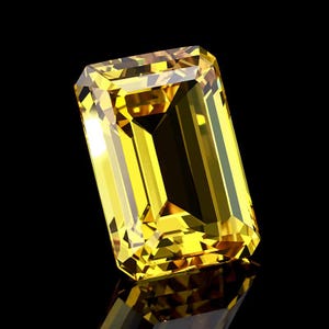 Könnte beinhalten: Ein strahlender, rechteckig geschliffener gelber Edelstein, möglicherweise ein Citrin oder gelber Saphir, vor schwarzem Hintergrund. Die Facetten des Edelsteins reflektieren das Licht und erzeugen ein brillantes Farb- und Funkeln. Der Edelstein ist im Smaragdschliff.