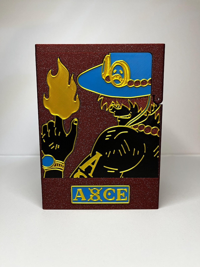 May include: A burgundy box featuring a character design with gold, black, and blue accents. The design includes a hat, a hand with a flame, and the word "ACE" in a blue rectangle.