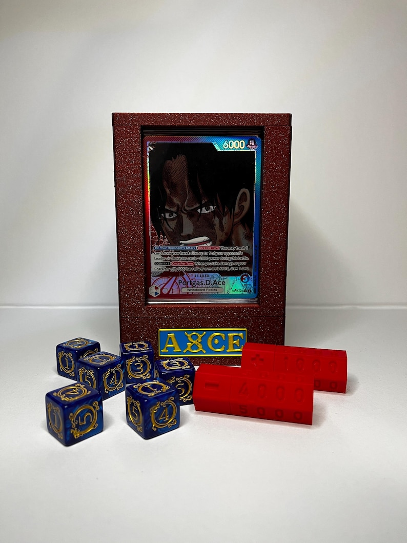 May include: A framed trading card featuring a character with dark hair and a determined expression. The frame is a deep red color, and the card is displayed with blue dice and red building blocks. The text "AXCE" is visible.