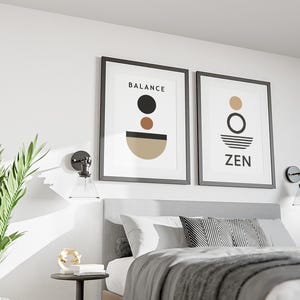 Peut inclure: Deux impressions encadrées avec des cadres noirs sont accrochées au-dessus d'un lit. L'une dit "BALANCE" et présente des formes noires, marron et beige. L'autre dit "ZEN" avec un cercle et des lignes. La pièce a une esthétique moderne et minimaliste.