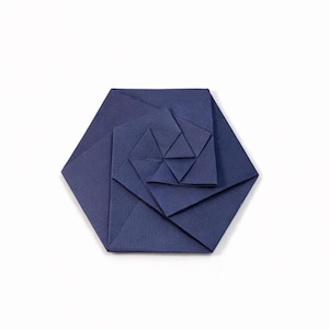 May include: A navy blue origami rose, meticulously folded from paper. The flower is composed of layered geometric shapes, creating a spiral effect. The hexagonal base supports the intricate design, showcasing the art of paper folding.