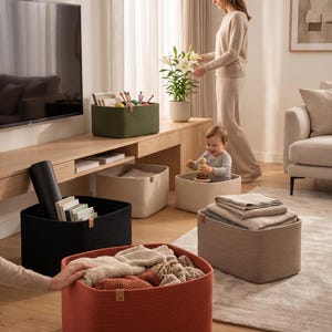 Puede incluir: Una colección de cestas de almacenamiento rectangulares hechas de cuerda enrollada en varios colores, incluyendo terracota, negro, verde oliva y beige. Cada cesta cuenta con una pequeña lengüeta de cuero en el lateral para organizar objetos.