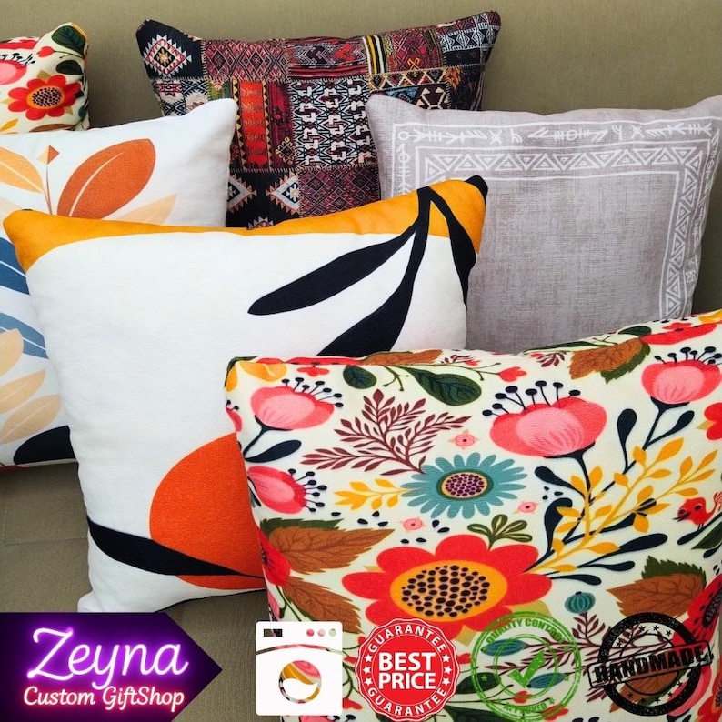 May include: A collection of decorative throw pillows with various patterns. Pillows feature floral, geometric, and abstract designs in colors like orange, white, black, and red. Some pillows have a yellow border. The image includes the text "Zeyna Custom GiftShop".