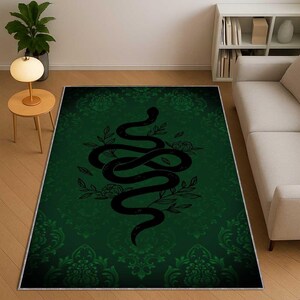 Pode incluir: Um tapete retangular verde com um desenho de cobra preta. A cobra está entrelaçada com elementos florais. O tapete tem um fundo com padrão de damasco verde escuro e uma borda branca.