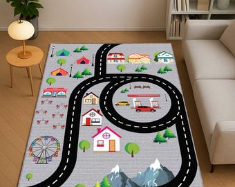 May include: A gray play rug with a road design, featuring a black road with white dashed lines. The rug includes illustrations of houses, trees, a Ferris wheel, and a gas station. The design is intended for children's play.