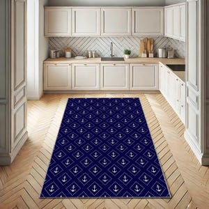 May include: A navy blue rectangular rug featuring a repeating pattern of white anchors within diamond shapes. The rug is positioned on a wooden floor in a kitchen, introducing a nautical theme to the room's decor.