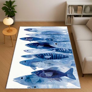 Könnte beinhalten: Rechteckiger Teppich mit einem Design aus blauen Fischen auf weißem Hintergrund. Die Fische sind in verschiedenen Blautönen dargestellt und erzeugen ein Gefühl der Bewegung. Der Teppich liegt auf einem hellen Holzboden.