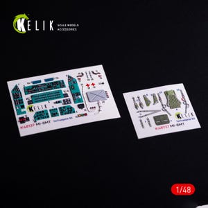 Op de afbeelding: Twee modelbouwstickervellen. Eén vel heeft een turquoise en zwart instrumentenpaneelontwerp met de tekst "KELIK" en "K48137 MI-BMT ForTrumpeter Kit". Het tweede vel heeft diverse modelaccessoires. De schaal is 1:48.