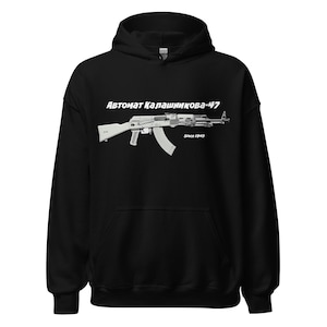 May include: Black hooded sweatshirt with a white graphic of an AK-47 assault rifle. The text above the rifle reads "Автомат Калашникова-47" and "Since 1949" is below the rifle. The sweatshirt is made of a soft material.