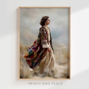 May include: A framed art print featuring a person with shoulder-length brown hair standing in a field of tall, dry grass. The person wears a long, cream-colored robe under a vibrant, multi-colored textured cloak. The text PRINTS AND PEACE is below.