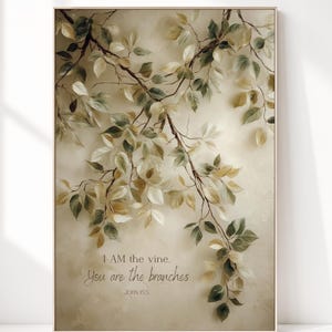 Può includere: Una stampa artistica da parete rettangolare che raffigura un ramo delicato con foglie verdi e beige su uno sfondo color crema strutturato. Il testo recita: I AM the vine. You are the branches. JOHN 15:5. La stampa è in una cornice sottile e chiara.