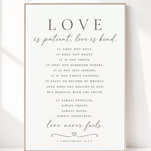 Pode incluir: Uma impressão de arte de parede retangular com o texto LOVE is patient, love is kind, seguido pela passagem completa de 1 Coríntios 13:4-8 em fontes serifadas e manuscritas cinza-escuras sobre fundo branco, em uma moldura de madeira clara.
