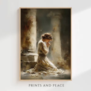 Può includere: Una stampa artistica incorniciata raffigura una persona inginocchiata in preghiera, vestita con un abito color crema fluente. L'opera d'arte ha uno stile morbido e pittorico con una tavolozza di colori tenui. Il testo "PRINTS AND PEACE" è in basso.