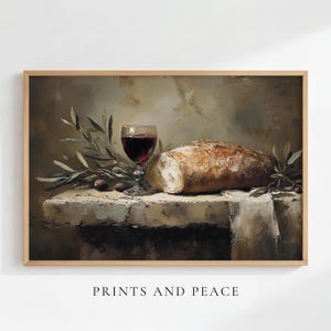 May include: A framed oil painting print featuring a still life composition with a glass of red wine, a crusty loaf of bread, and olive branches resting on a stone surface. The text PRINTS AND PEACE is centred below the artwork.