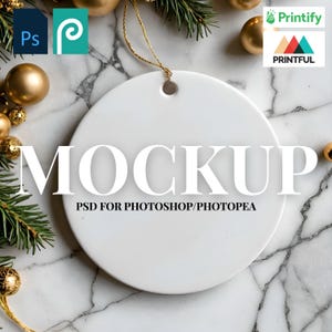 May include: A white ceramic round ornament mockup with the word "MOCKUP" in large white letters. The text "PSD FOR PHOTOSHOP/PHOTOPAE" is below. The background includes gold ornaments, pine needles, and a marble surface.
